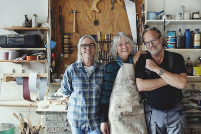 Portrait of male and female senior coworkers standing against tools at workshop