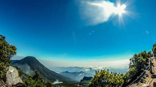 Scenic view of mountains against blue sky on sunny day