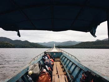 Bags in boat on river against cloudy sky