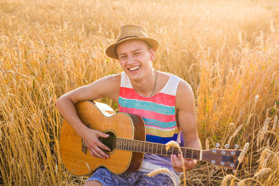 Smiling man playing guitar on field