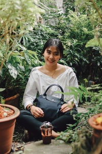 Portrait of a smiling young woman holding food outdoors