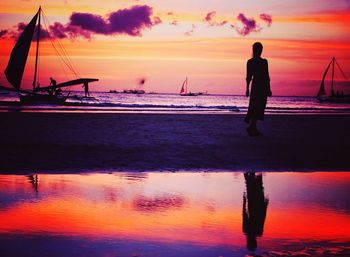 Silhouette man on beach against sky during sunset