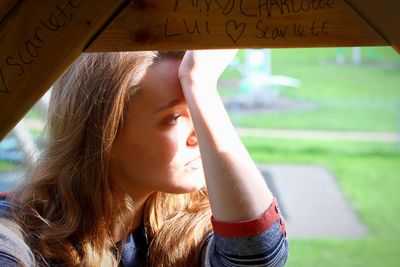 Side view of young woman by wood