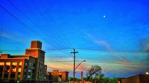 Low angle view of electricity pylon against blue sky