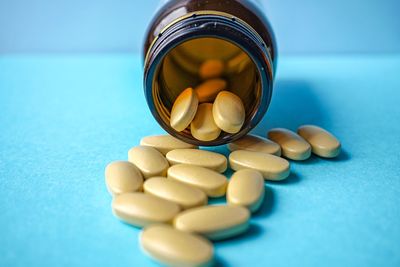 Close-up of pills spilling from bottle on blue background