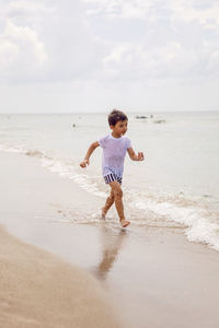 Full length of boy running at beach