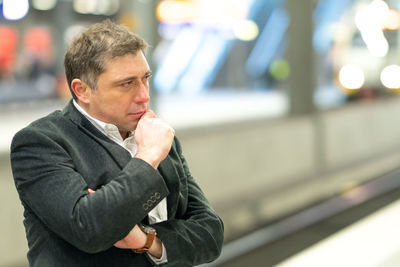 Side view of thoughtful businessman standing at railroad station platform