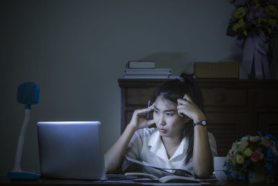 Young woman using mobile phone while sitting on table