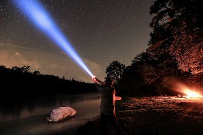 Woman standing by lake against sky at night