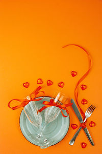 High angle view of glasses on table against orange background