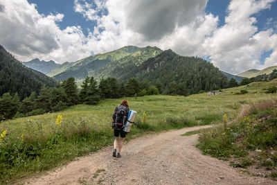 Full length rear view of man walking on road against sky