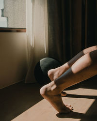 Low section of person relaxing on hardwood floor at home