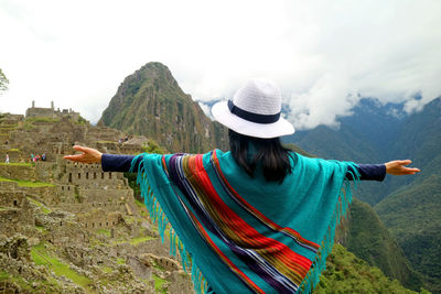 Rear view of woman standing by mountain against sky