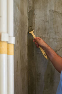 Putting on isolation material with a brush in a wall corner