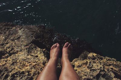 Low section of woman on rock at beach