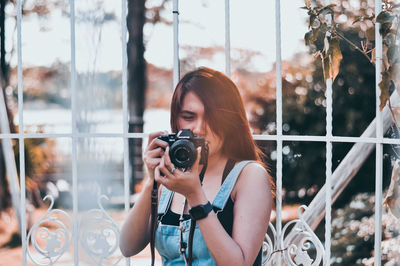 Young woman photographing through window