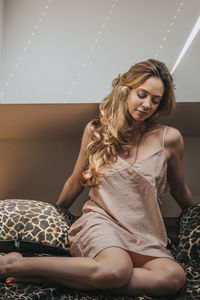 Young woman sitting on bed at home