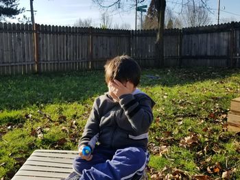 Rear view of boy standing by plants against sky