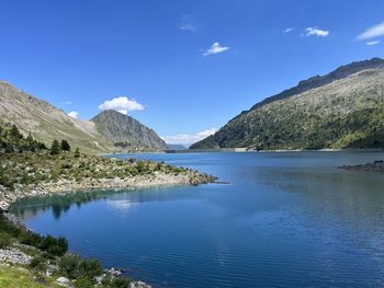 Scenic view of lake and mountains against blue sky