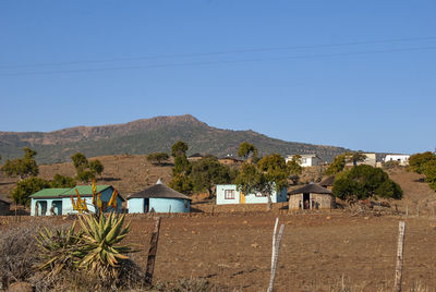 Houses by mountains against clear blue sky