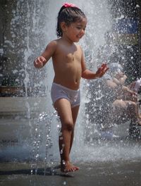 Full length of shirtless boy splashing water