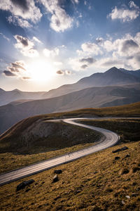 Scenic view of road by mountains against sky