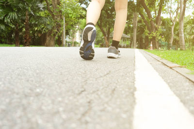 Low section of woman walking on road