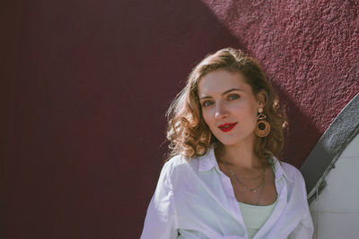 Portrait of smiling woman by wall