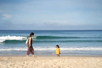 Rear view of woman on beach against sky