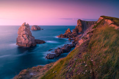 Rock formation on sea against sky during sunset