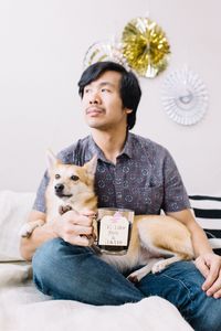 Thoughtful man with dog holding drink at home