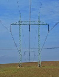 Low angle view of electricity pylon on field against sky