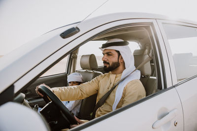 Father and son sitting in car at desert