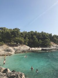 People swimming in sea against sky