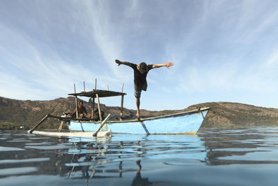 Male surfer with outstretched arms plunging into sea