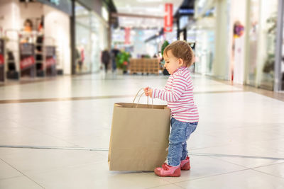 Full length of boy looking away while standing on tiled floor