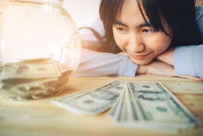 Close-up of smiling young woman with paper currency on table