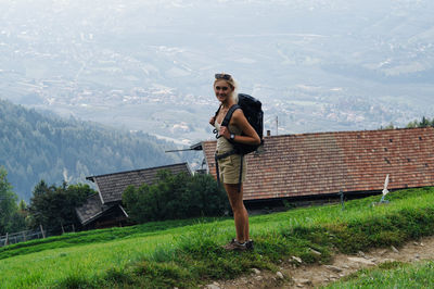 Portrait of woman carrying backpack while standing against landscape