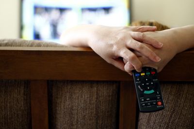 Woman holding remote while watching tv