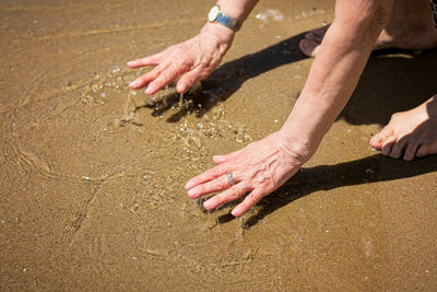 Elderly attractive woman touching the water on the seashore