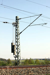 Electricity pylon on railroad track against sky