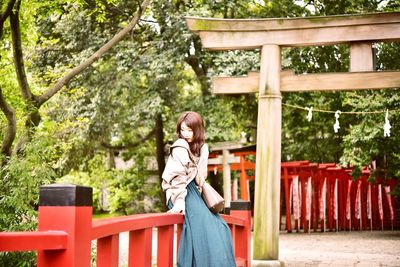 Side view of woman standing against torii gate