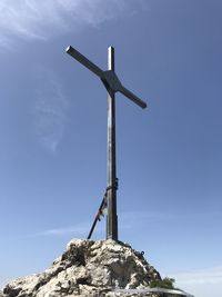 Low angle view of cross on rock against sky