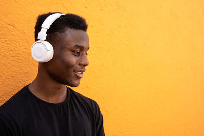 Portrait of smiling young man standing against yellow wall