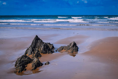 Scenic view of rocks on beach against sky