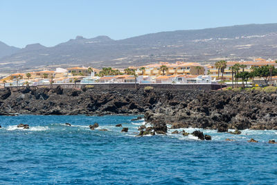 Scenic view of sea and buildings against clear sky