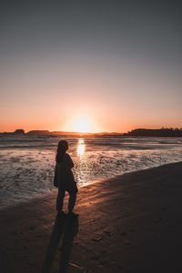 Silhouette man standing on beach against sky during sunset