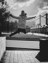 Rear view of man jumping against sky