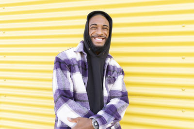 Portrait of smiling young man standing against yellow wall