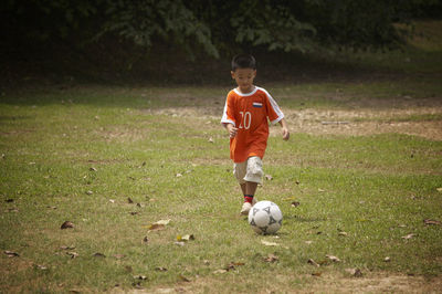 Full length of boy playing soccer on field at park